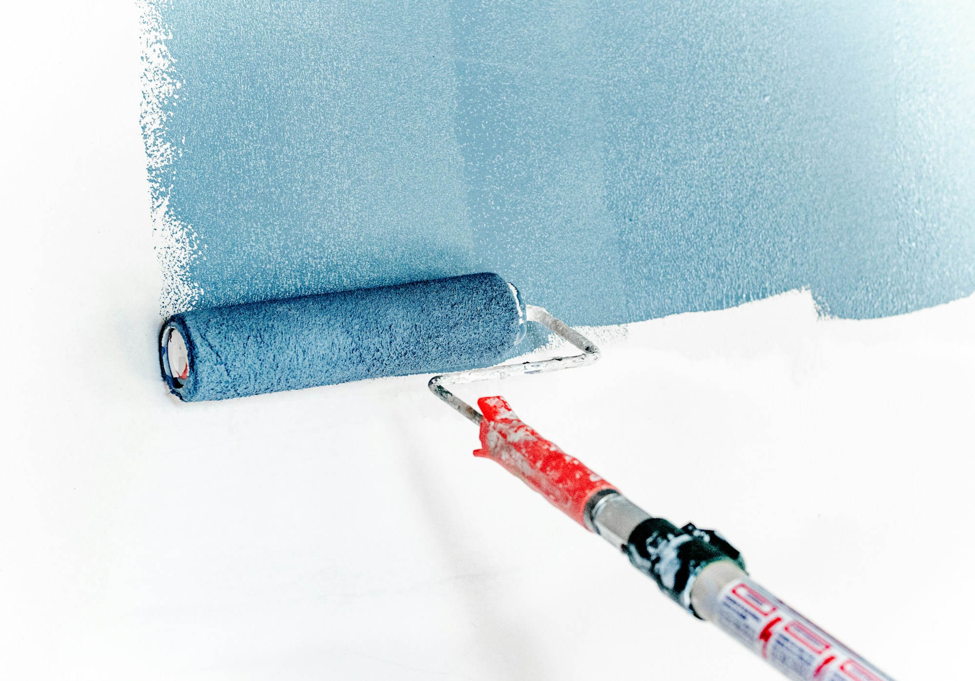 Paint roller applying blue paint; stock finishing reference