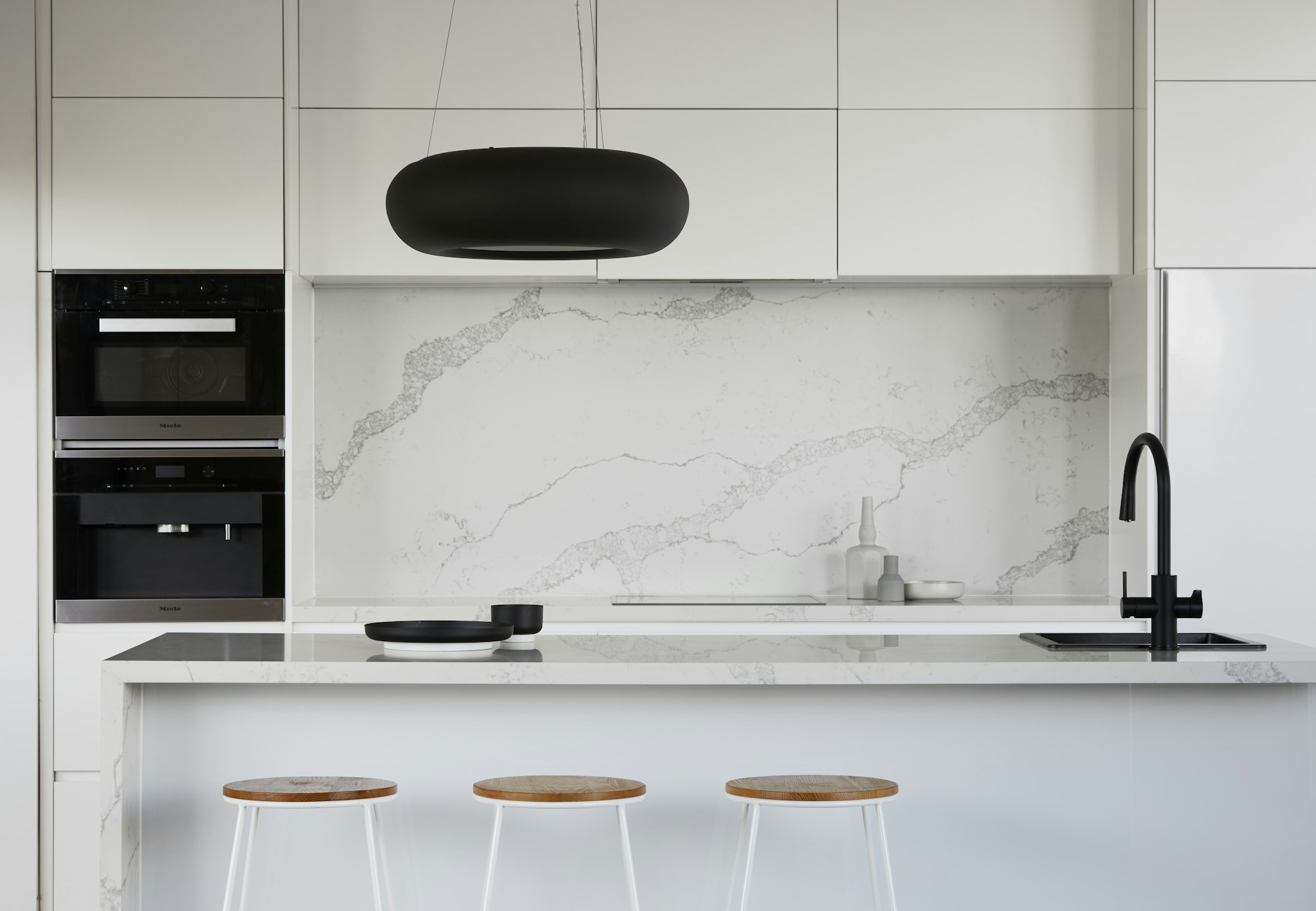 White kitchen cabinetry and a veined stone splashback; stock reference
